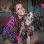 Alternative looking hippy style woman sitting down inside and boho home, wearing an Alex Tooth Radiant Bloom Sanctum Hoodie.
