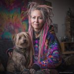 Alternative looking hippy style woman sitting down inside and boho home, wearing an Alex Tooth Inner Flight Sanctum Hoodie.