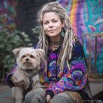 Alternative looking hippy style woman sitting down outside wearing an Alex Tooth Inner Flight Sanctum Hoodie.
