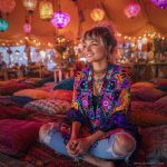 Alternative looking hippy style woman seated wearing an Alex Tooth Inner Flight Ritual Wrap shawl cover up.