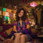 Alternative looking hippy style woman seated wearing an Alex Tooth Inner Flight Ritual Wrap shawl cover up.