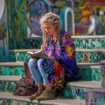 Alternative looking hippy style woman seated wearing an Alex Tooth Inner Flight Ritual Wrap shawl cover up.
