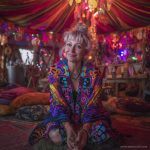Alternative looking hippy style woman seated wearing an Alex Tooth Inner Flight Ritual Wrap shawl cover up.