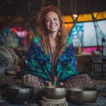Alternative looking hippy style woman seated wearing an Alex Tooth Emerald StarGate Ritual Wrap shawl cover up.