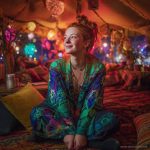 Alternative looking hippy style woman seated wearing an Alex Tooth Emerald StarGate Ritual Wrap shawl cover up.