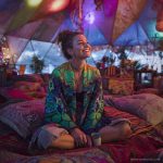 Alternative looking hippy style woman seated wearing an Alex Tooth Emerald StarGate Ritual Wrap shawl cover up.