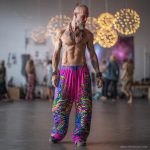 Alternative looking hippy style man inside a yoga studio wearing Alex Tooth Radiant Bloom FlowState Pants.