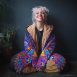 Alternative hippy boho style woman sitting down outside wearing buckle up fleece lined Alex Tooth Inner Flight Vision Robe.