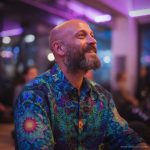 Smart looking alternative hippy style man standing in a inside social function setting wearing an Alex Tooth Emerald StarGate InnerLight Shirt.