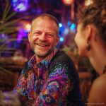 Smart looking alternative hippy style man sitting inside a boho cafe / restaurant setting wearing an Alex Tooth Inner Flight InnerLight Shirt.