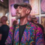Alternative edgy looking hippy man standing looking cool wearing an Alex Tooth Radiant Bloom Wayfarer Blazer.