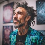 Alternative edgy looking hippy man standing looking cool wearing an Alex Tooth Emerald StarGate Wayfarer Blazer.
