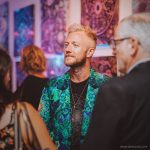 Alternative edgy looking hippy man standing looking cool wearing an Alex Tooth Emerald StarGate Wayfarer Blazer.