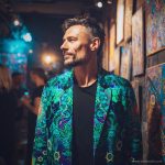Alternative edgy looking hippy man standing looking cool wearing an Alex Tooth Emerald StarGate Wayfarer Blazer.