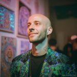 Alternative edgy looking hippy man standing looking cool wearing an Alex Tooth Emerald StarGate Wayfarer Blazer.