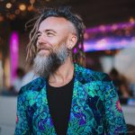 Alternative edgy looking hippy man standing looking cool wearing an Alex Tooth Emerald StarGate Wayfarer Blazer.