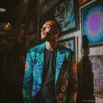 Alternative edgy looking hippy man standing looking cool wearing an Alex Tooth Emerald StarGate Wayfarer Blazer.