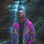 Alternative hippy looking man standing outside wearing Alex Tooth Radiant Bloom Pathfinder Jacket.