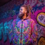 Alternative hippy looking man standing outside wearing Alex Tooth Radiant Bloom Pathfinder Jacket.