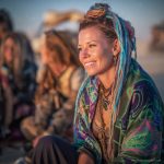 Edgy looking alternative hippy woman smiling, sitting down outside, wearing Alex Tooth Emerald StarGate Waylight Scarf.