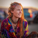 Edgy looking alternative hippy woman smiling, sitting down outside, wearing Alex Tooth Inner flight Waylight Scarf.