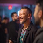 Man at social function, wearing wearing Alex Tooth Emerald StarGate Long Sleeved Balance Tee T-Shirt underneath his blazer.