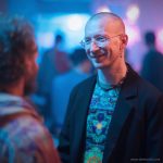 Man at social function, wearing wearing Alex Tooth Emerald StarGate Long Sleeved Balance Tee T-Shirt underneath his blazer.