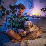 Man chilling on sofa with dog reading, wearing wearing Alex Tooth Emerald StarGate Long Sleeved Balance Tee T-Shirt.