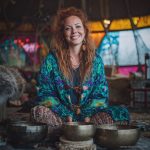 Alternative hippy boho style woman sitting down inside wearing buckle up fleece lined Alex Tooth Emerald StarGate Vision Robe.