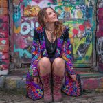 Alternative looking hippy woman sitting outside smiling, wearing long zip up fleece lined Alex Tooth Inner Flight Ritual Robe