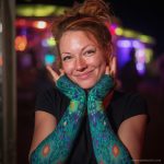 Alternative looking hippy style woman smiling, wearing Alex Tooth Emerald StarGate Aurasleeve Gloves.