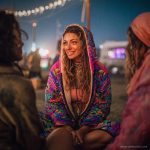 Alternative looking hippy woman sitting outside smiling, wearing long zip up fleece lined Alex Tooth Radiant Bloom Ritual Robe
