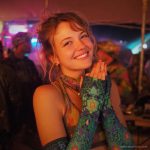 Alternative looking hippy style woman smiling, wearing Alex Tooth Emerald StarGate Aurasleeve Gloves.
