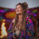 Alternative looking hippy woman standing outside wearing long zip up fleece lined Alex Tooth Radiant Bloom Ritual Robe