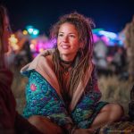 Alternative looking hippy woman sitting outside smiling, wearing long zip up fleece lined Alex Tooth Emerald StarGate Ritual Robe