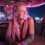 Alternative looking hippy style woman smiling, wearing Alex Tooth Radiant Bloom Aurasleeve Gloves.