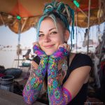 Alternative looking hippy style woman smiling, wearing Alex Tooth Radiant Bloom Aurasleeve Gloves.