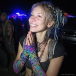 Alternative looking hippy style woman smiling, wearing Alex Tooth Radiant Bloom Aurasleeve Gloves.
