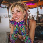 Alternative looking hippy style woman smiling, wearing Alex Tooth Radiant Bloom Aurasleeve Gloves.