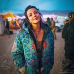 Alternative looking hippy style woman in a winter season outdoor setting wearing an Alex Tooth Emerald StarGate Nomad Coat Long Puffer Winter Coat.