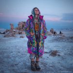 Alternative looking hippy style woman in a winter season outdoor setting wearing an Alex Tooth Radiant Bloom Nomad Coat Long Puffer Winter Coat.