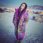 Alternative looking hippy style woman in a winter season outdoor setting wearing an Alex Tooth Radiant Bloom Nomad Coat Long Puffer Winter Coat.