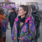 Alternative looking hippy style woman in a winter season outdoor setting wearing an Alex Tooth Radiant Bloom Nomad Coat Long Puffer Winter Coat.